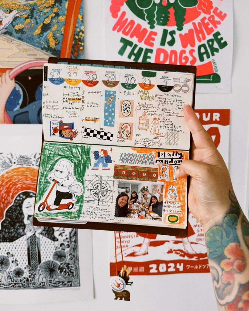 Hand holding a creative, colorful journal with doodles, notes, and a photo collage against a vibrant wall backdrop.