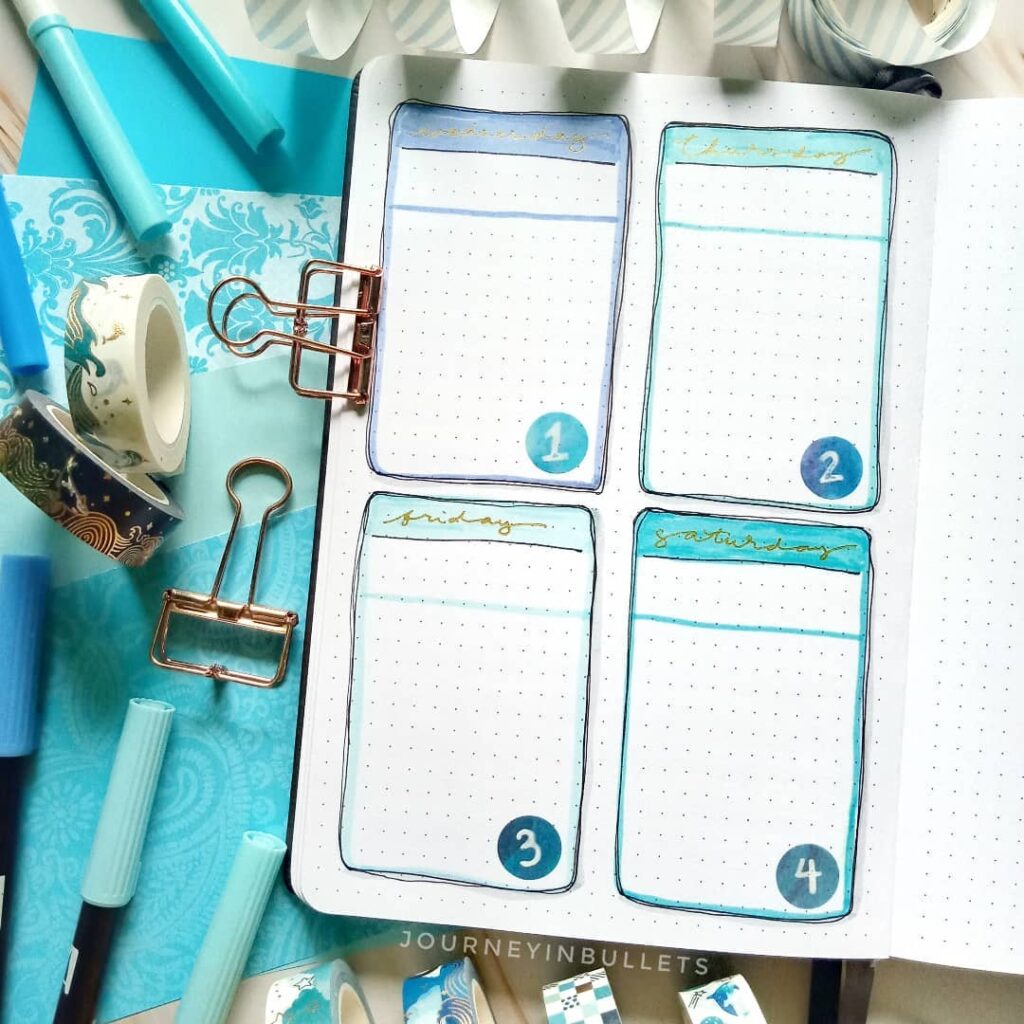 Bullet journal layout with blue markers, washi tape, binder clips, and decorative paper, showcasing creative planning.