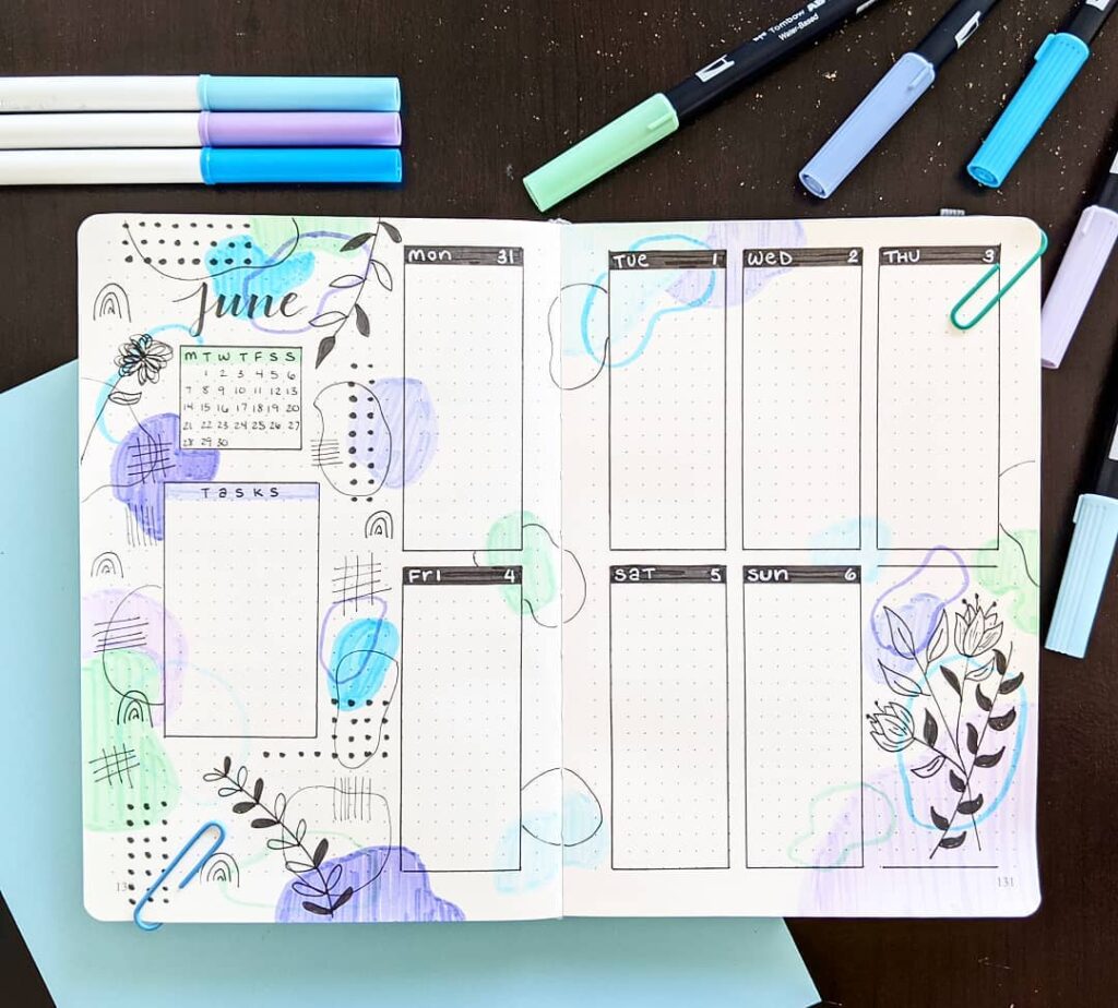 Decorative June bullet journal planner with colorful doodles and pens on a desk.