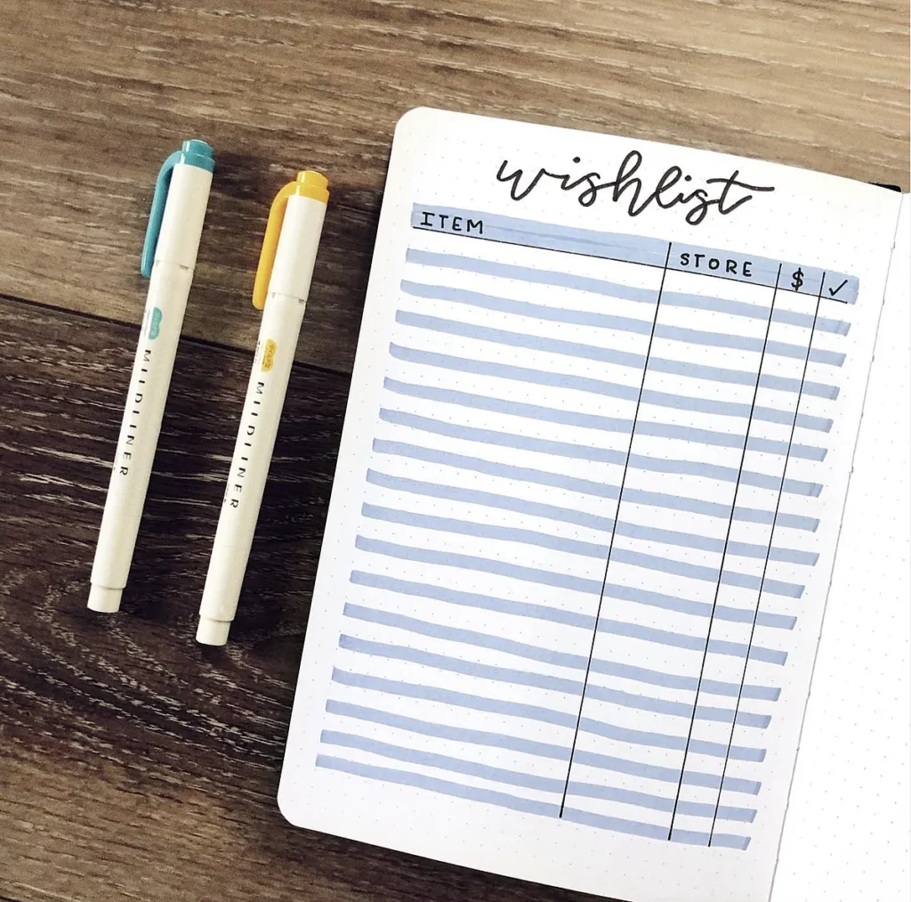 Notebook wishlist with lines and two colored pens on a wooden desk.