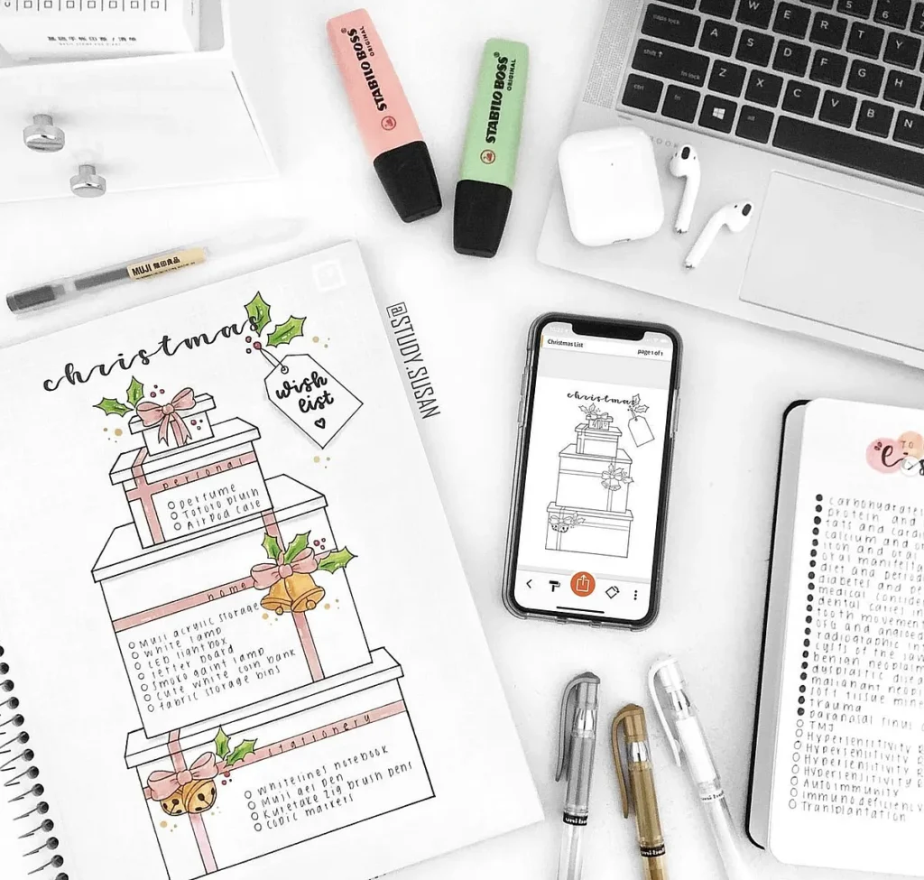 Christmas wish list with gift boxes on a desk with highlighters, pens, and a smartphone. Minimalist stationery setup.