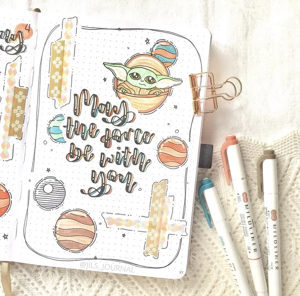 Decorated journal page with May the force be with you text, featuring planets and art pens on the side.