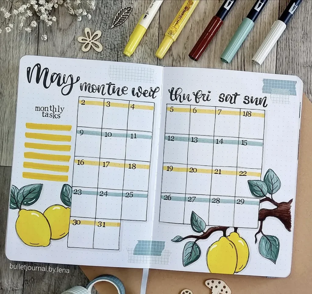 Bullet journal for May with lemon theme, featuring a calendar and space for monthly tasks. Pens and decor in frame.