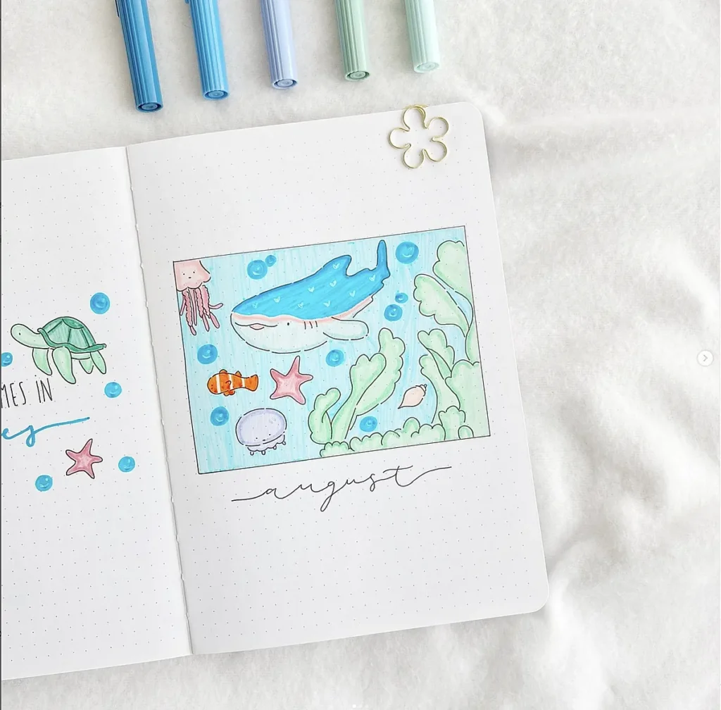 Bullet journal featuring cute sea life doodles for August with pens and paperclip on a white background.