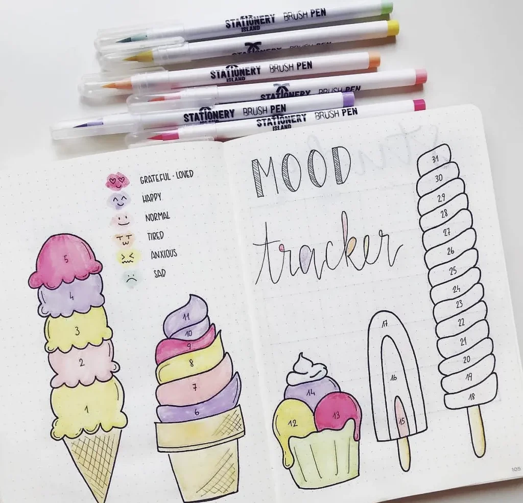 Colorful mood tracker in a bullet journal with ice cream and popsicle drawings alongside brush pens.