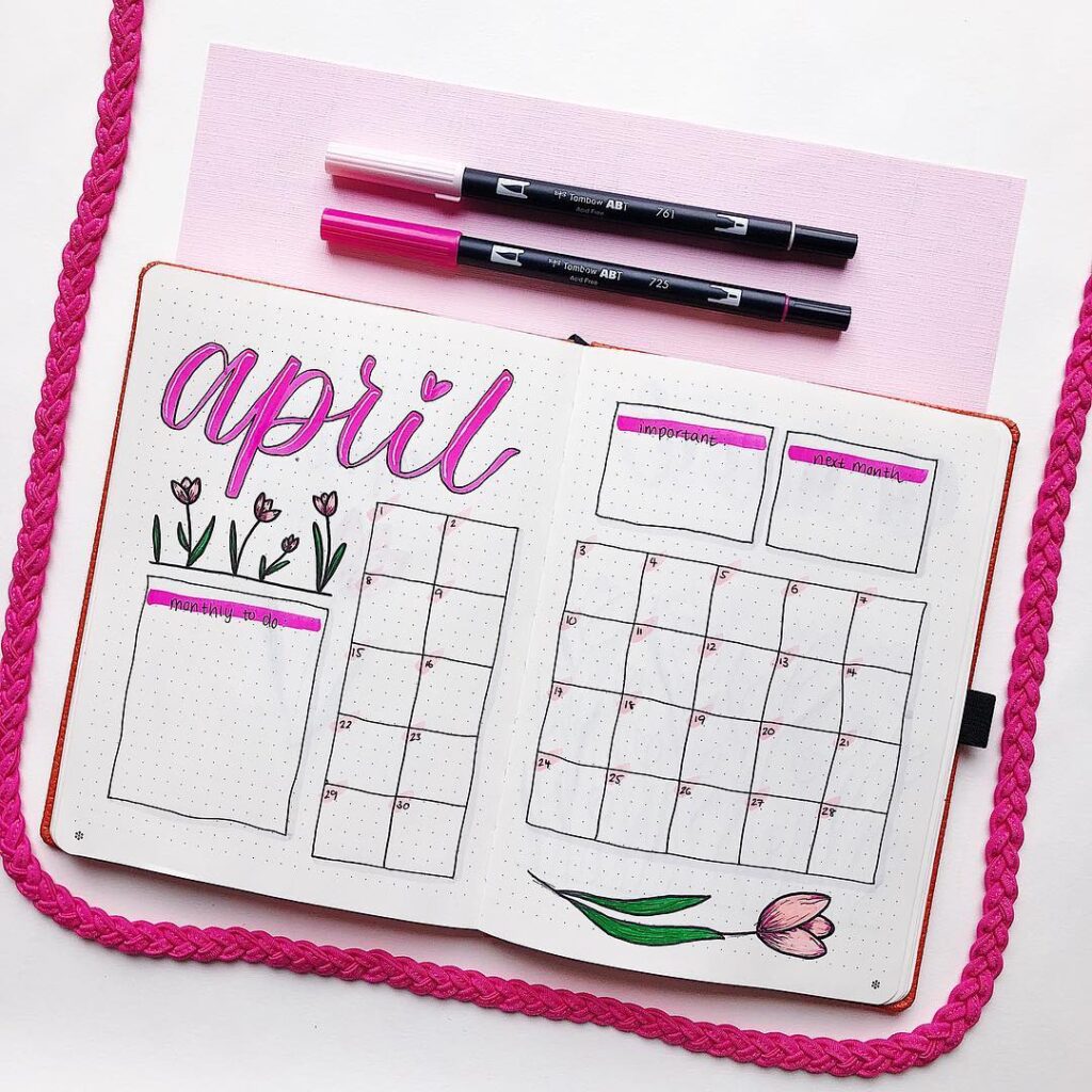April bullet journal spread with pink accents, featuring a calendar, tulip drawing, and colored pens.
