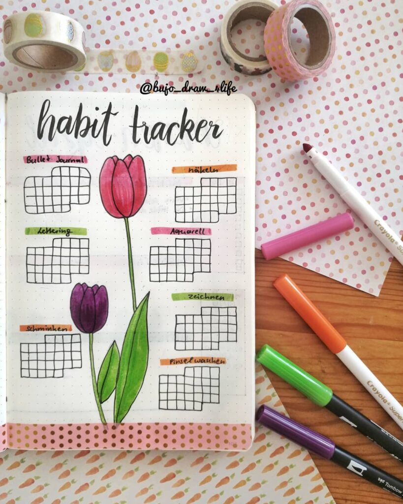Bullet journal habit tracker with colorful tulips, washi tape, and markers on a polka dot background.