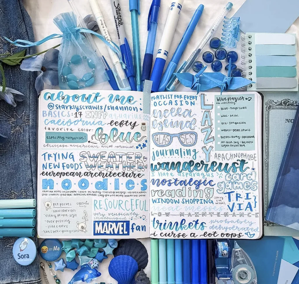 Blue-themed bullet journal spread with pens and accessories, showcasing personal interests and playlists in creative fonts.