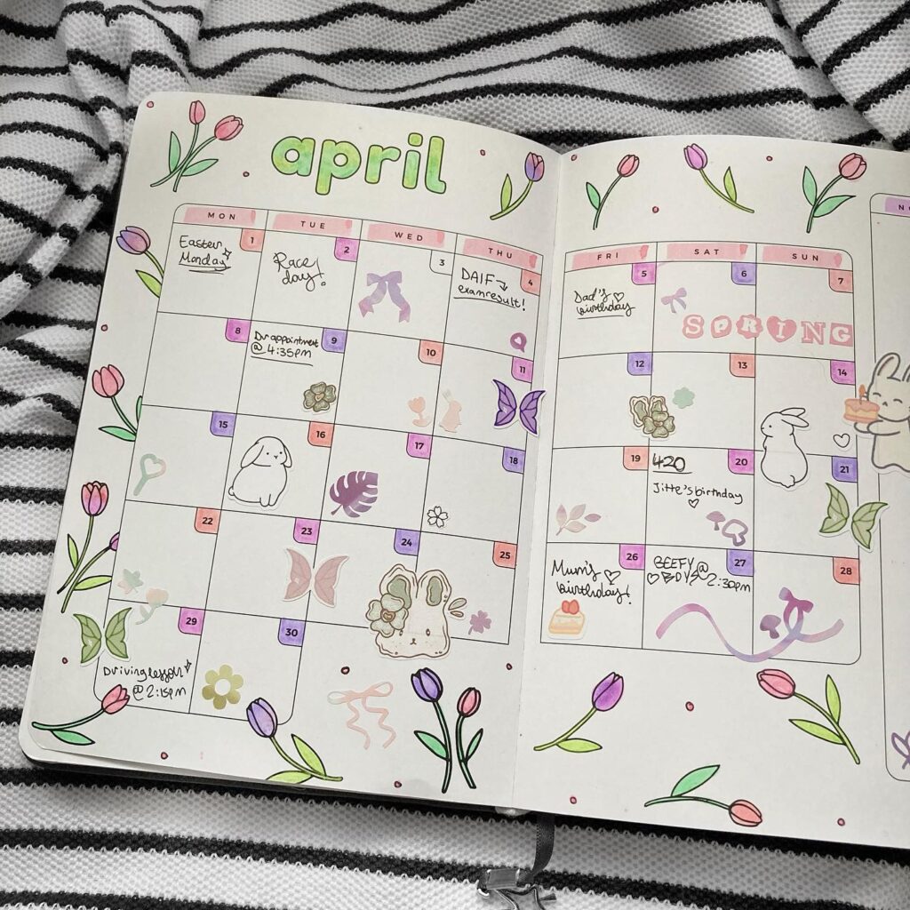 April calendar with floral doodles and notes for Easter, birthdays, and events on a striped fabric background.