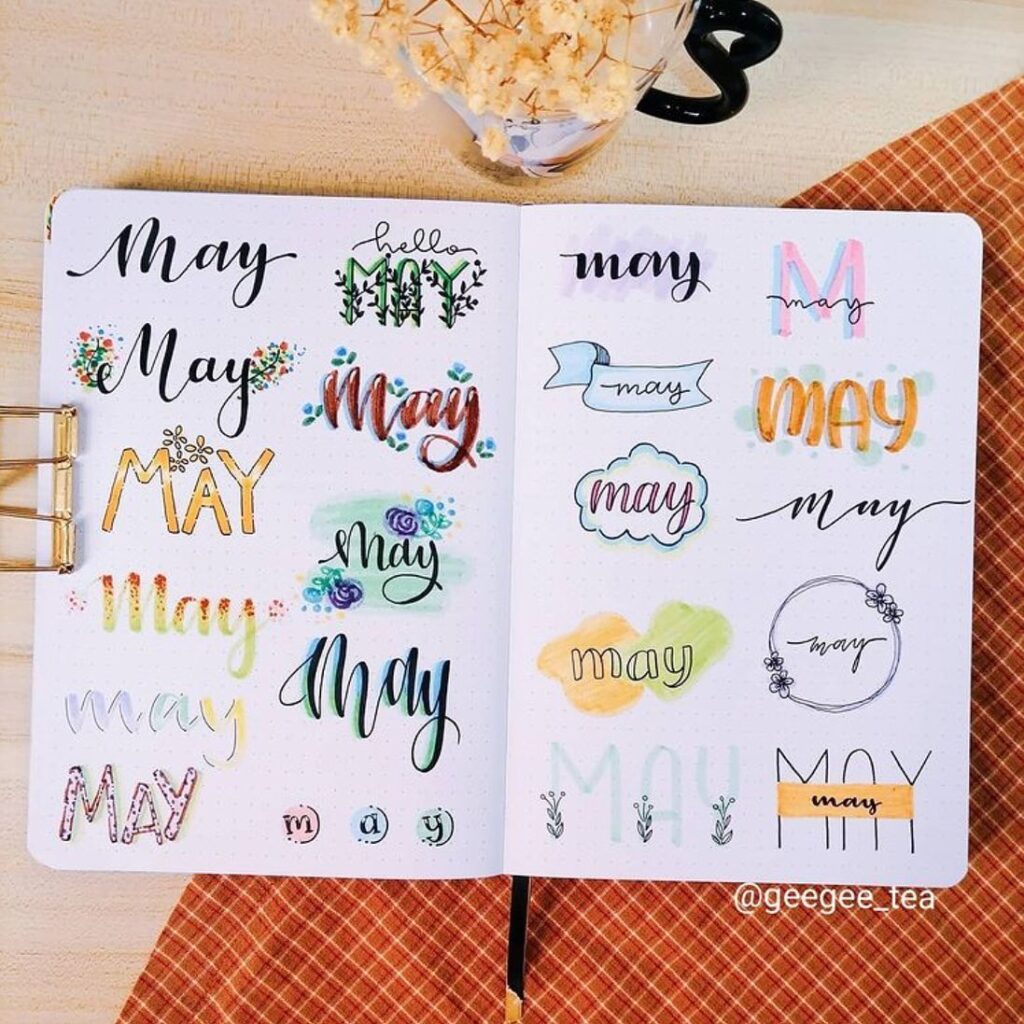 Bullet journal page with various May calligraphy styles, featuring colorful and decorative designs.