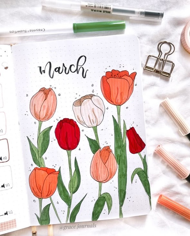 Bullet journal March tulip illustration with colorful pens and stationery items nearby.