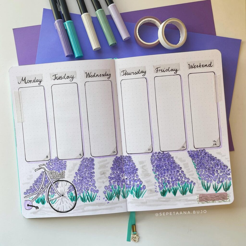 Weekly planner with lavender field illustration, markers, washi tapes, and purple paper for bullet journaling.