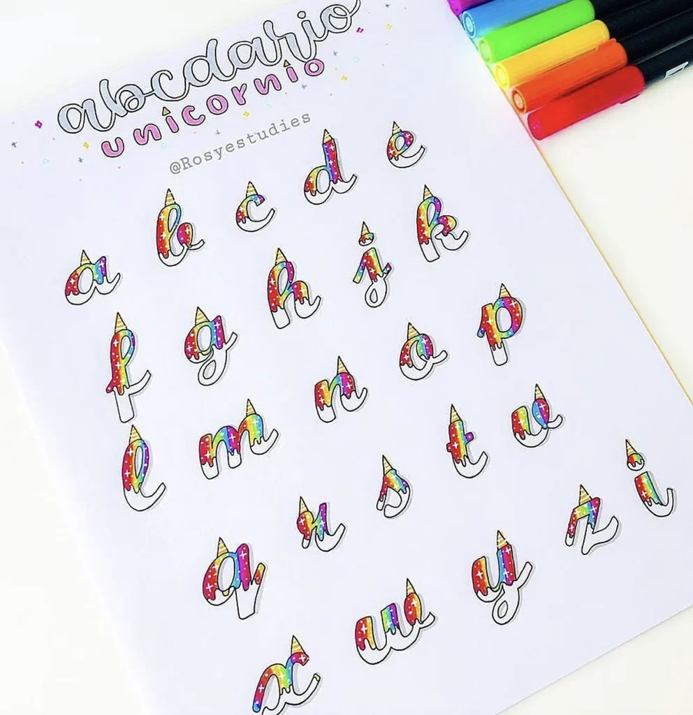 Colorful unicorn-themed alphabet letters on paper with markers, featuring whimsical design and rainbow accents.