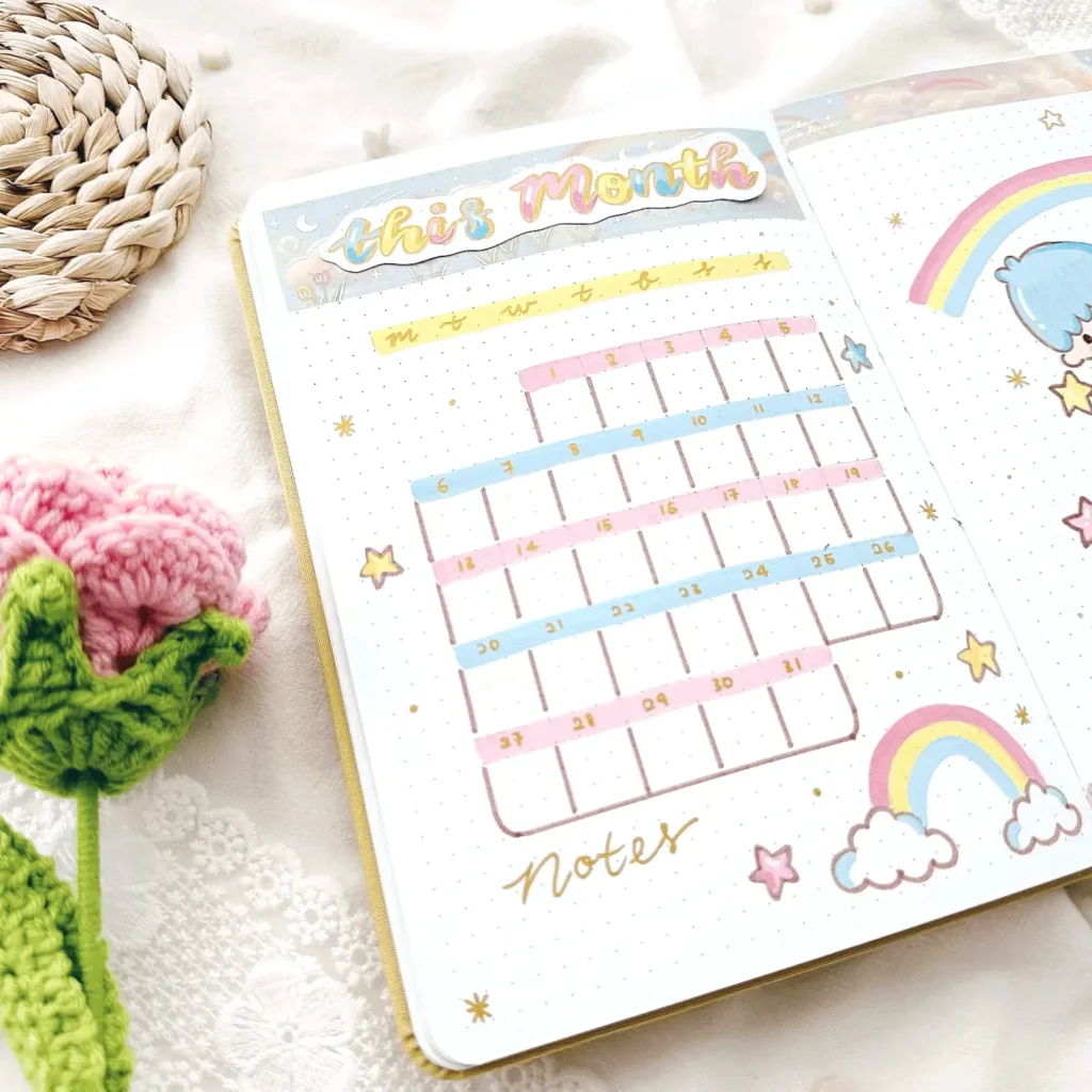 Cute monthly planner with colorful calendar and decorative elements like rainbows and crochet flowers on lace fabric.