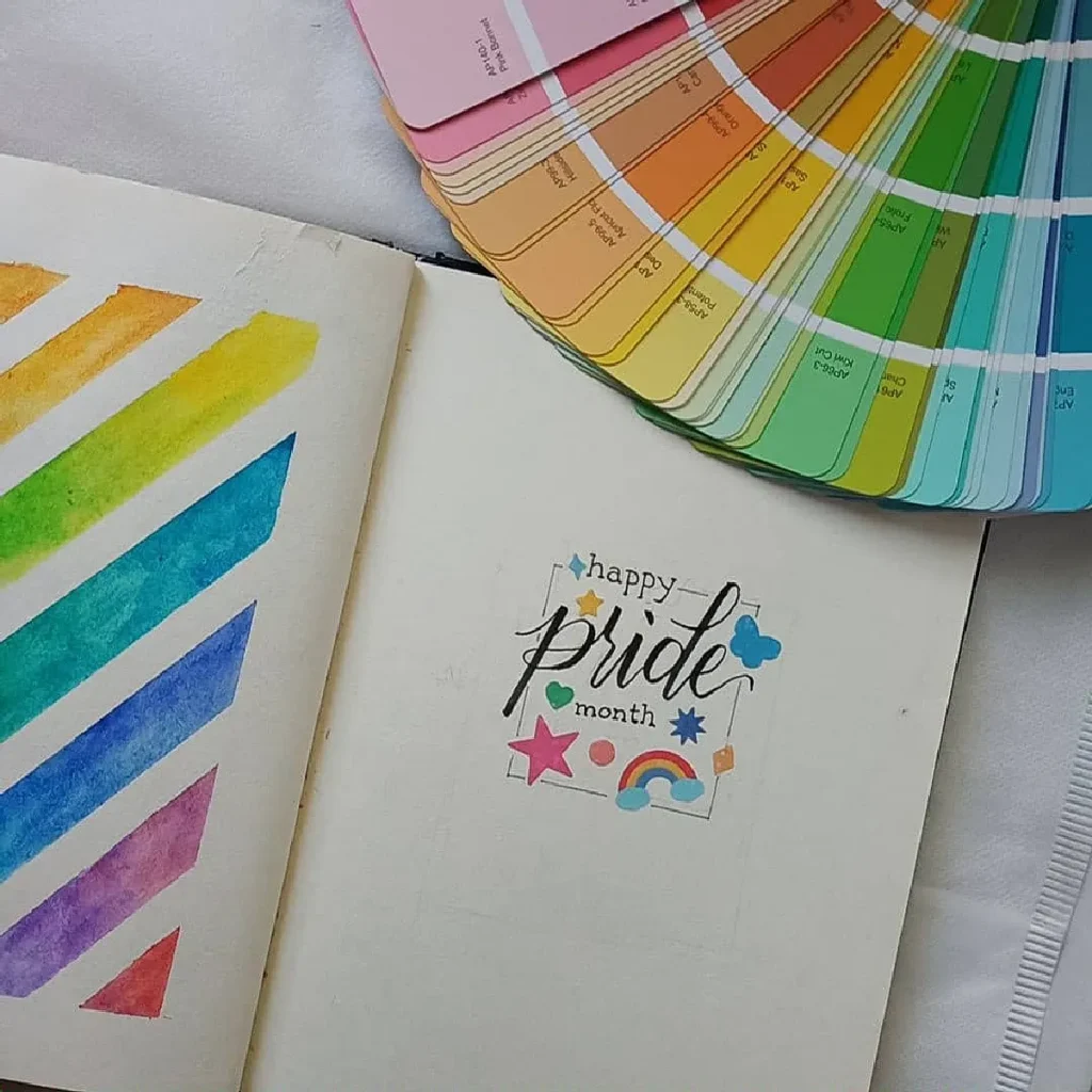 Colorful Pride Month journal with rainbow watercolor, decorations, and paint swatches. Celebrate diversity and creativity.