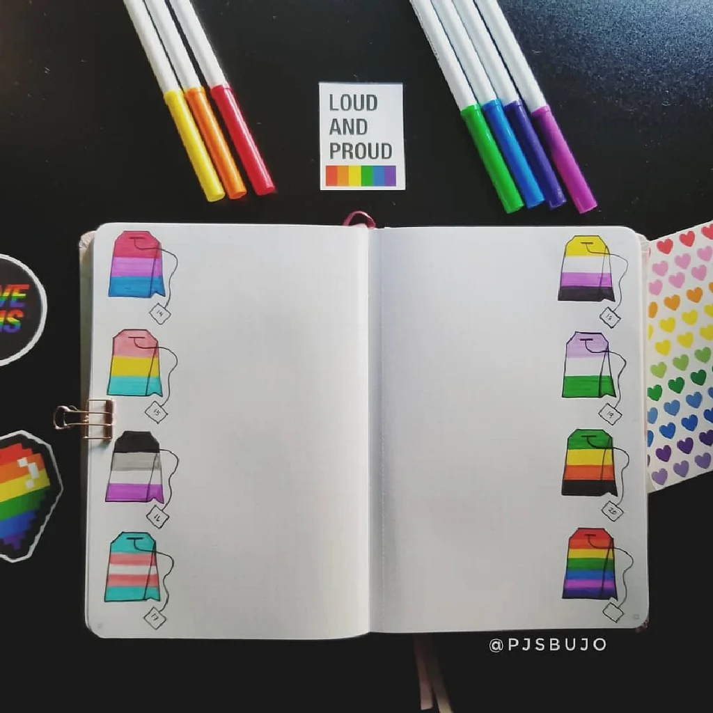 Open journal with colorful pride flag drawings and pens, surrounded by stickers. LGBTQ+ themed stationery set.