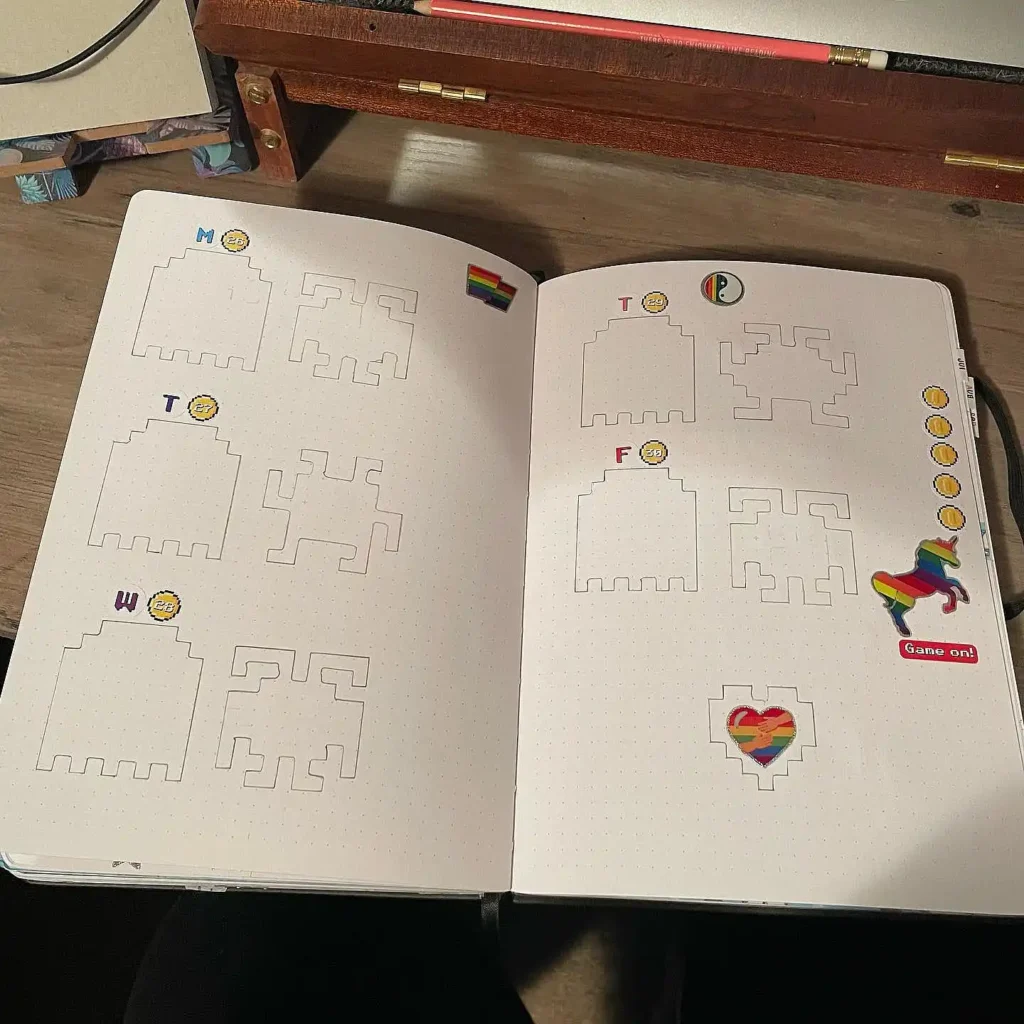 Open journal with grid designs, rainbow stickers, and colorful accents on a wooden desk.