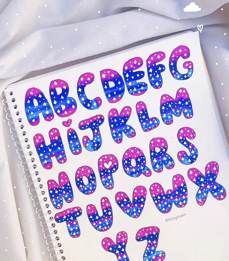 Colorful hand-drawn alphabet letters with star patterns on a spiral-bound notebook. Vibrant and artistic design.
