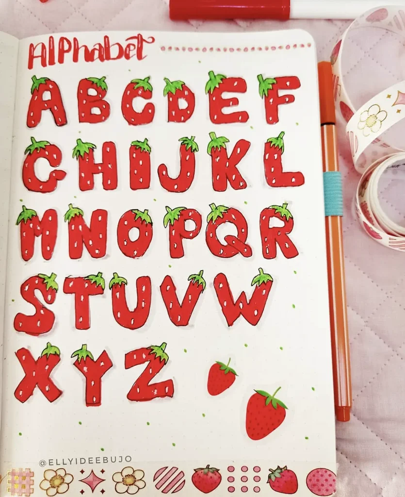 Hand-drawn strawberry-themed alphabet in a notebook, showcasing creative lettering design.