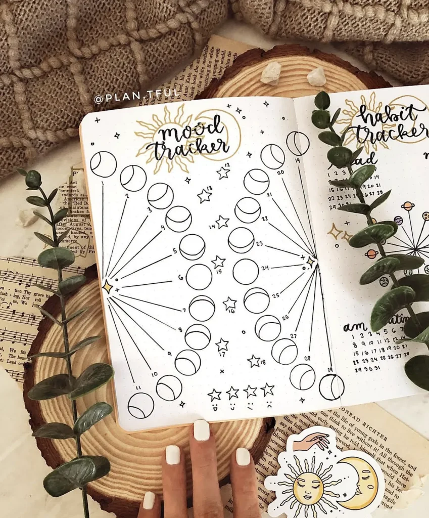 Bullet journal mood and habit tracker with celestial designs surrounded by plants and cozy textures.