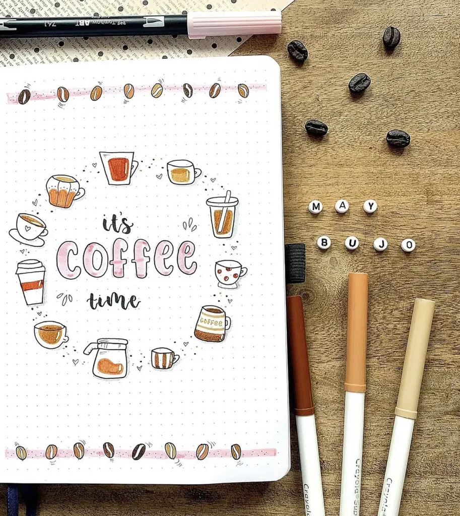 Bullet journal page with coffee-themed illustrations, text it's coffee time, and pens on a wooden table.