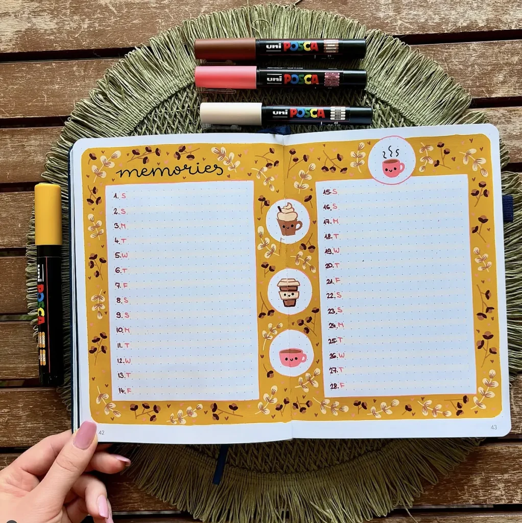 Open bullet journal with decorative pages for memories, surrounded by Posca pens on a straw mat.
