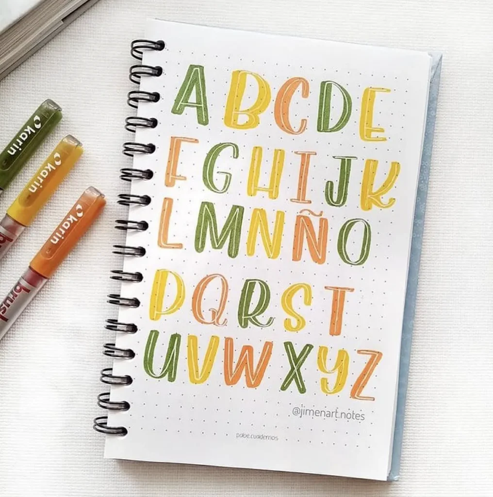 Colorful alphabet art in a notebook with markers.