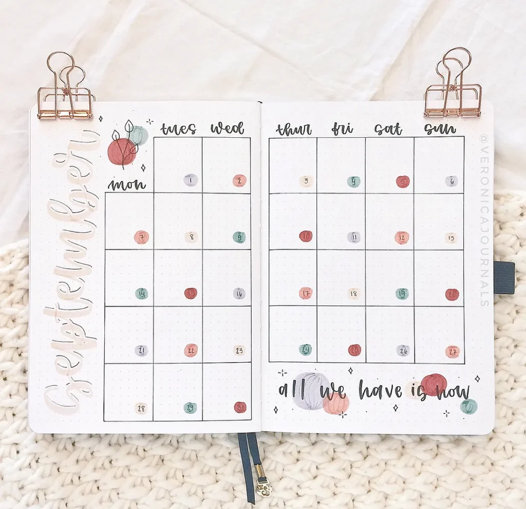 September bullet journal layout with colorful circles and motivational quote, All We Have Is Now, on cozy knitted background.