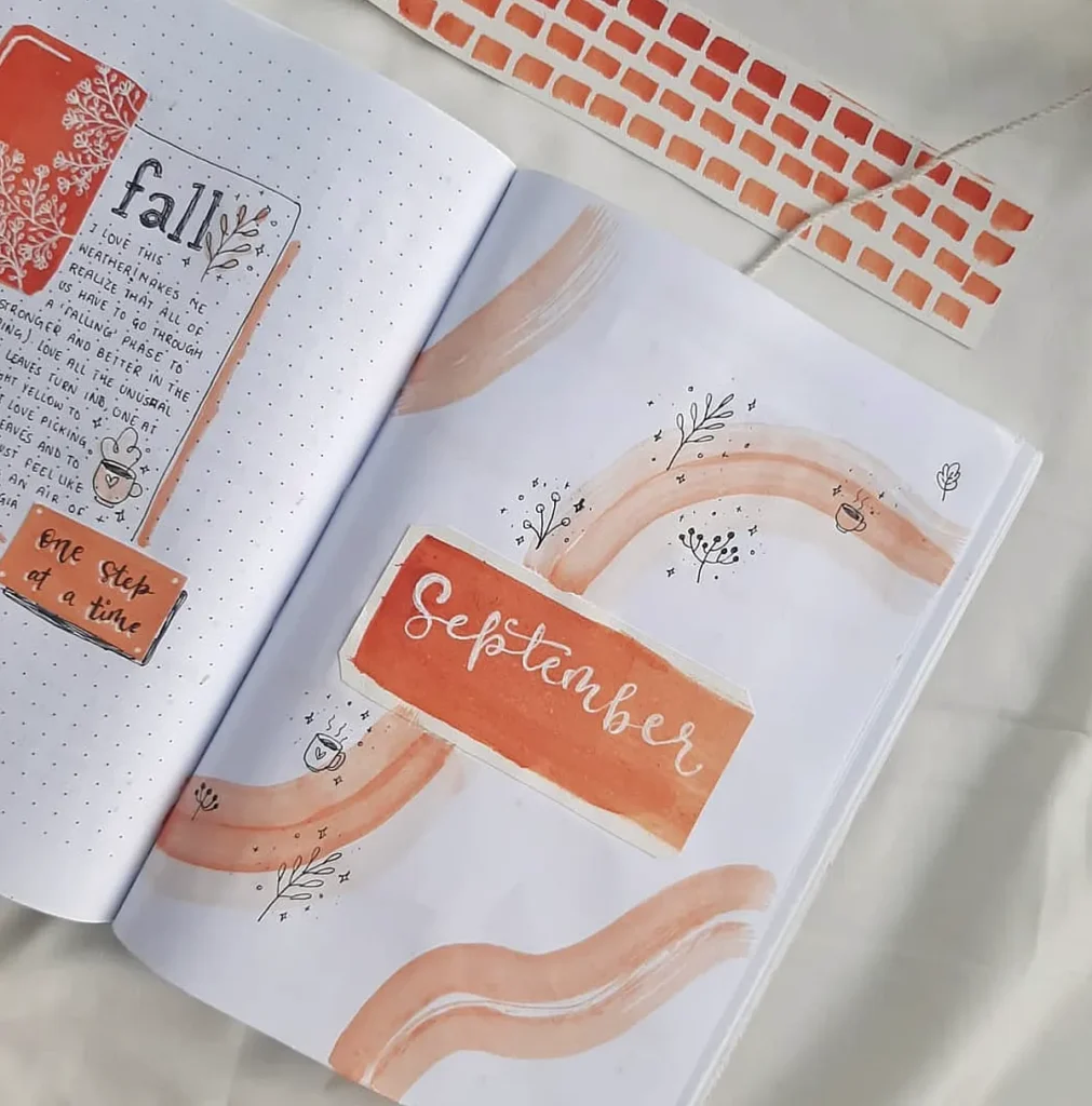 Open journal with artistic pages labeled September and fall, featuring autumn-themed designs and pastel colors.