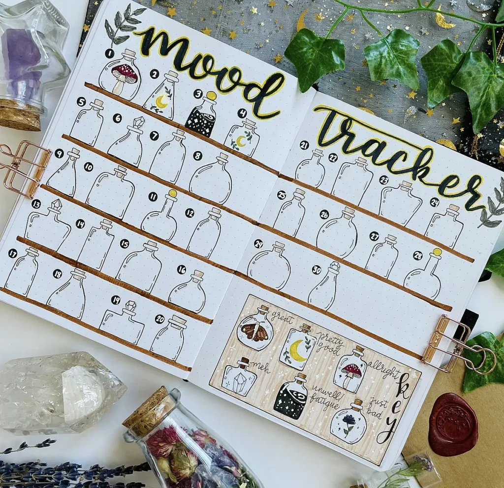 Bullet journal mood tracker with decorative bottles, surrounded by crystals and leaves. Ideal for mental health tracking.