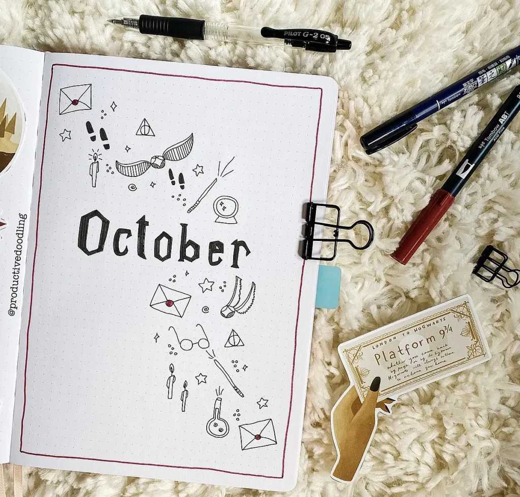 Bullet journal open to October, decorated with Harry Potter-themed doodles, surrounded by pens on a cozy surface.