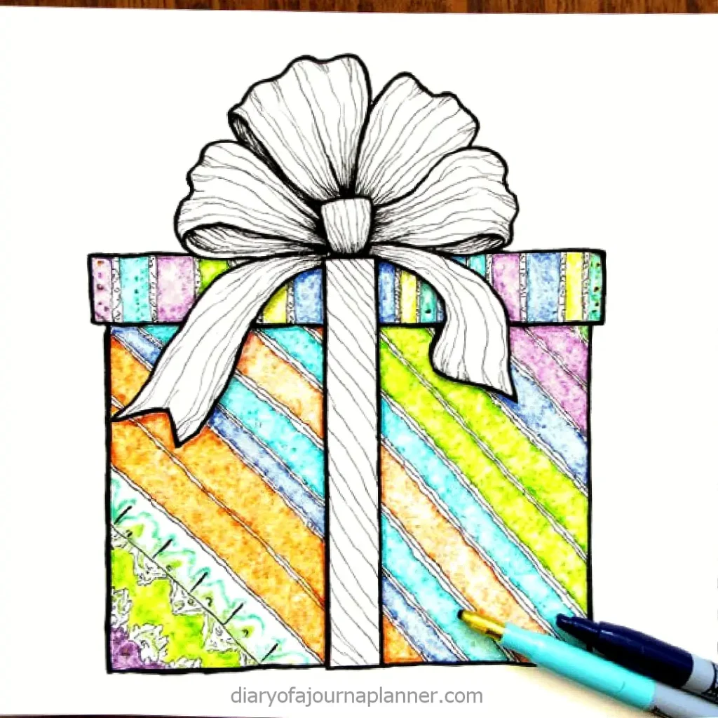 Colorful gift box with ribbon, rainbow stripes, and markers. Perfect for creative holiday art or festive decorations.