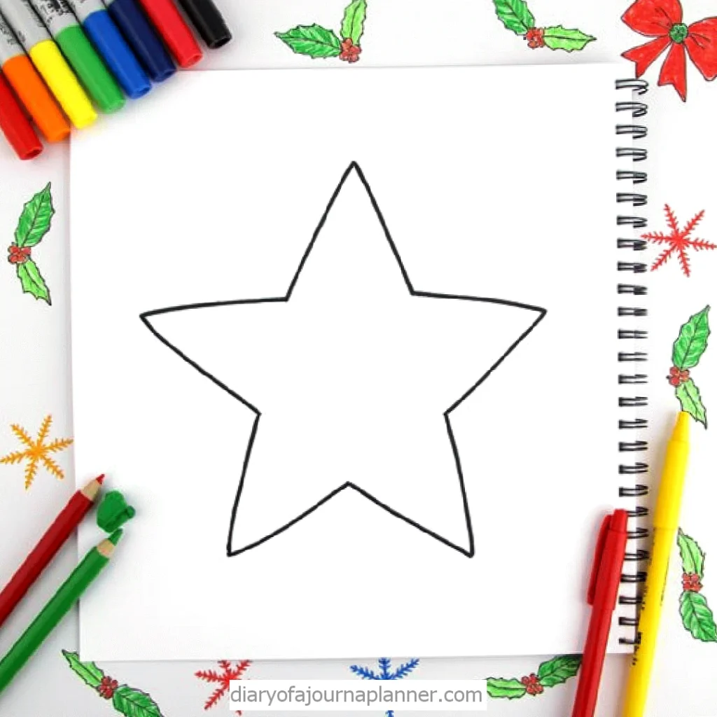 Star outline drawing surrounded by markers and holiday-themed decorations on a sketchbook page.
