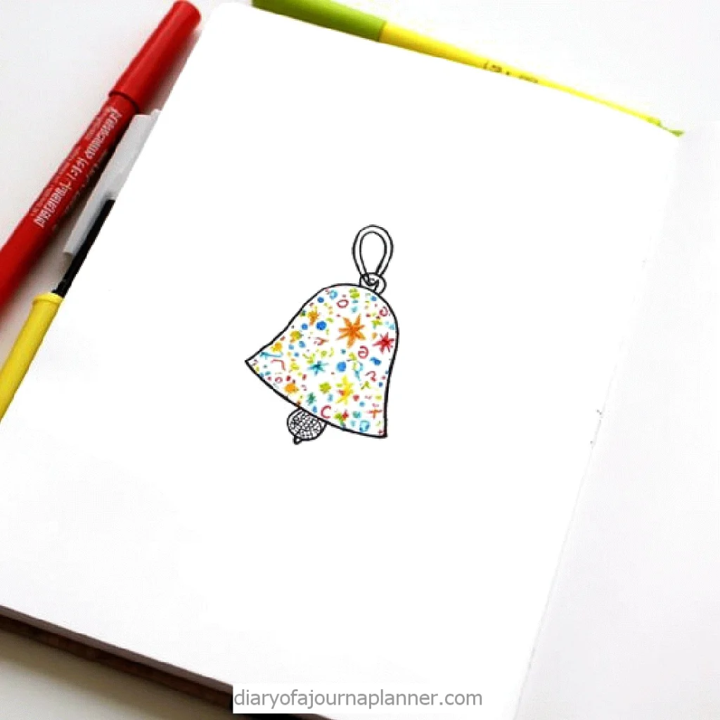 Colorful hand-drawn Christmas bell with doodles on a journal page, surrounded by pens.