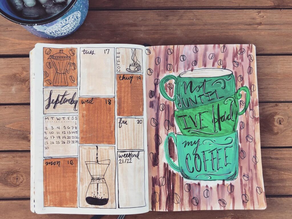 Open journal with illustrated coffee-themed calendar and green cups saying Not until I've had my coffee.