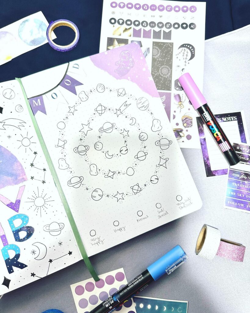 Astro-themed bullet journal with doodles and stickers, featuring planets and stars for mood tracking.