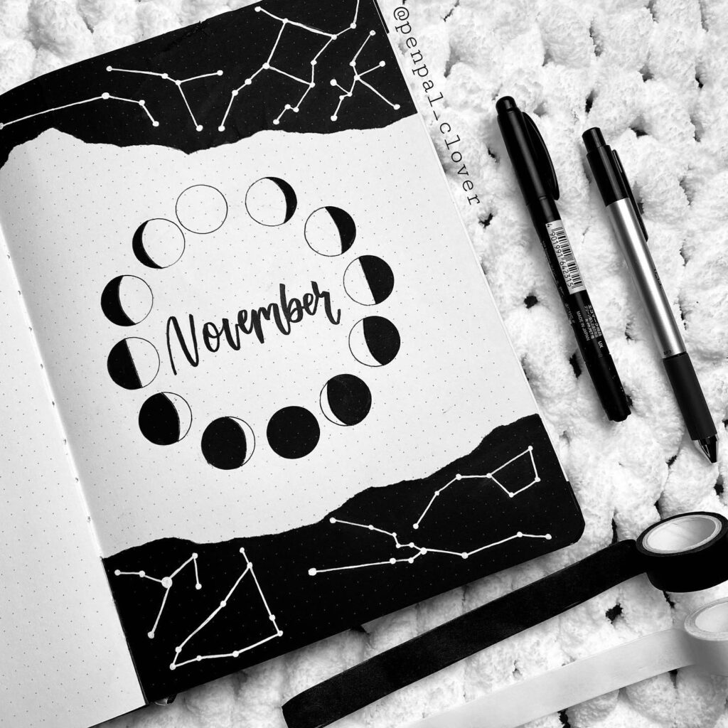 November bullet journal layout with moon phases, constellation art, pens, and washi tape. Black and white theme.