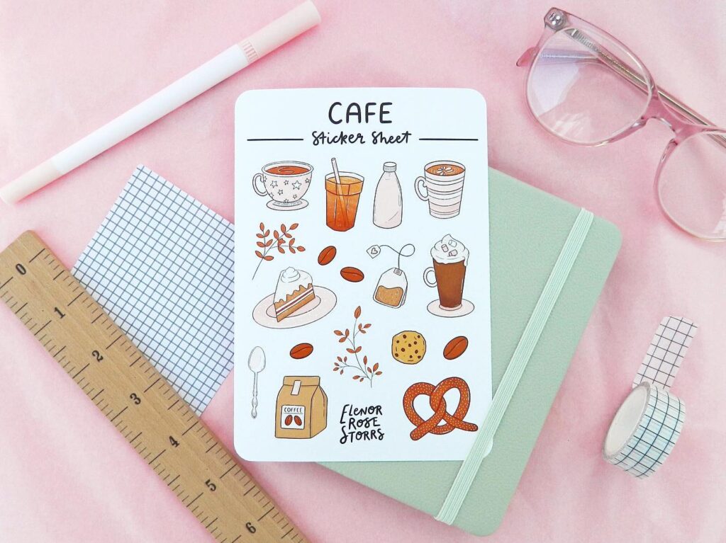 Cafe-themed sticker sheet with coffee, pastries, and drinks on a desk with glasses, a notebook, and stationery.