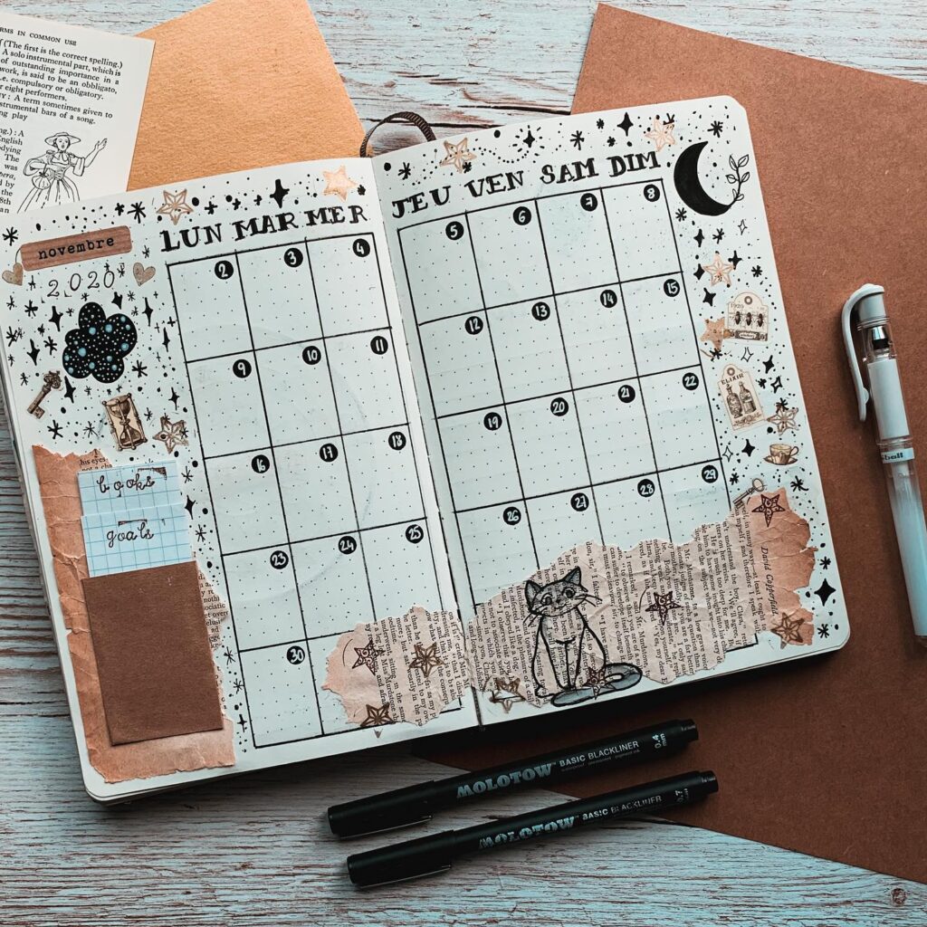 Decorated bullet journal open to November, with goals section, pens, and vintage-style embellishments.