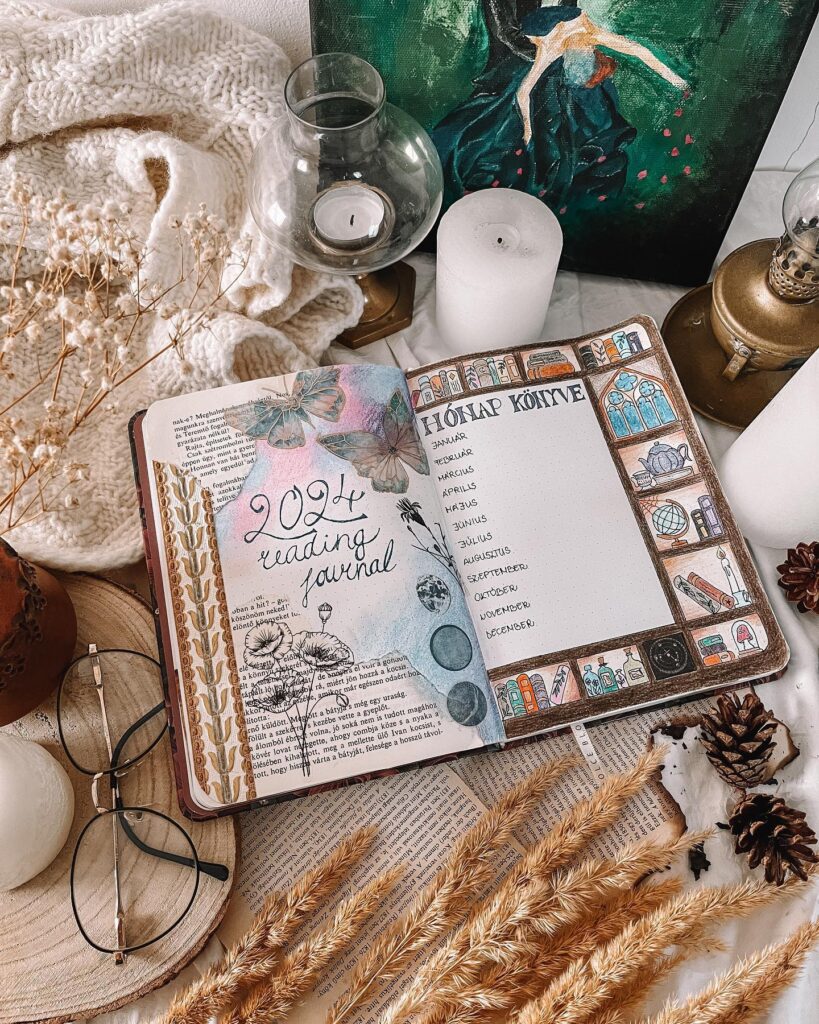 Cozy 2024 reading journal with calendar layout, surrounded by candles, dried flowers, and glasses on a textured surface.