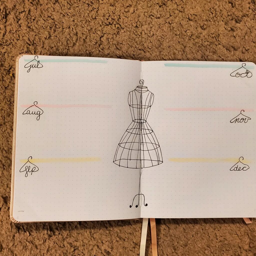 Bullet journal open to a page with a dress form sketch and monthly headings, located on a textured carpet background.