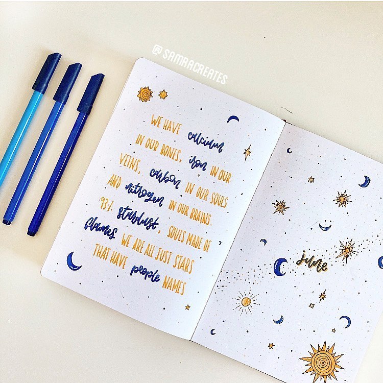 Decorative journal with blue pens, handwritten inspirational quote about stardust, and celestial illustrations for June.