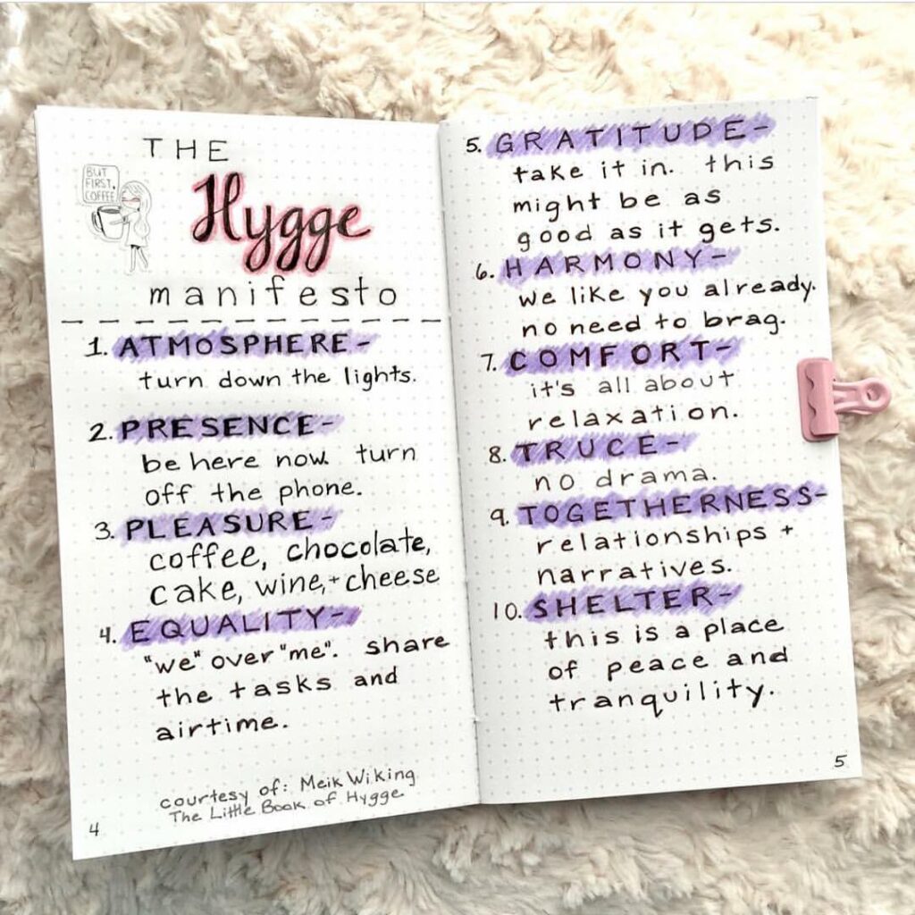 Handwritten hygge manifesto notebook page with 10 principles for coziness and well-being, emphasizing atmosphere and togetherness.