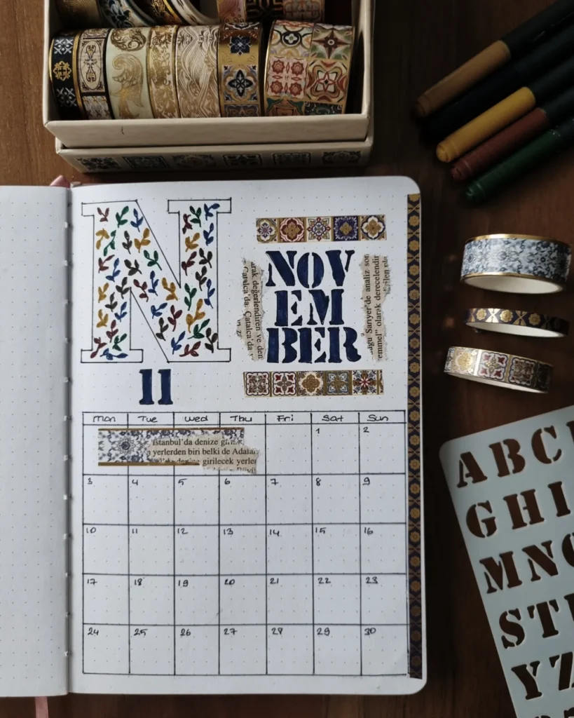 Decorative bullet journal calendar for November with washi tape and markers on a wooden table.