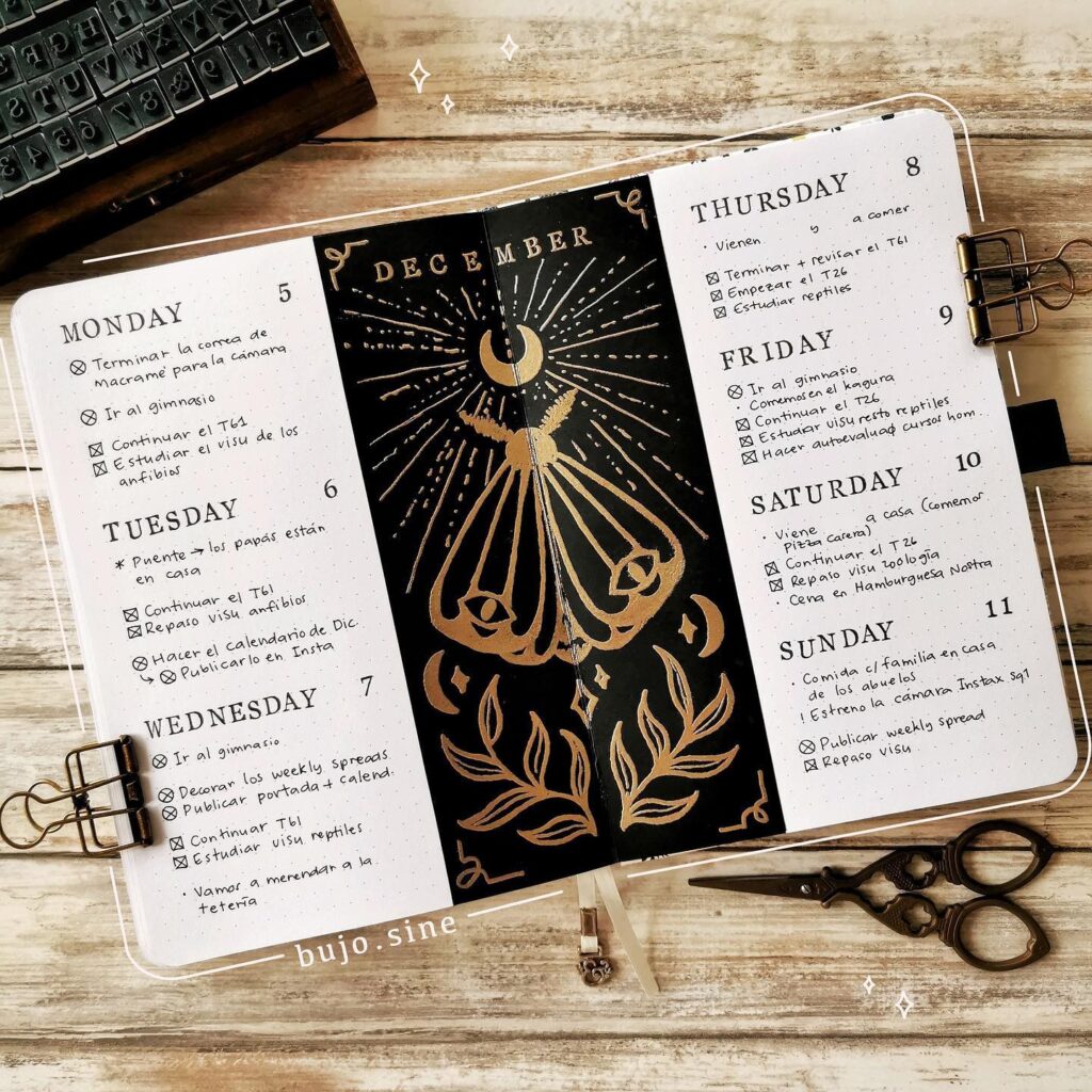 December bullet journal spread with celestial design, daily tasks, and decorative gold details on a wooden desk.