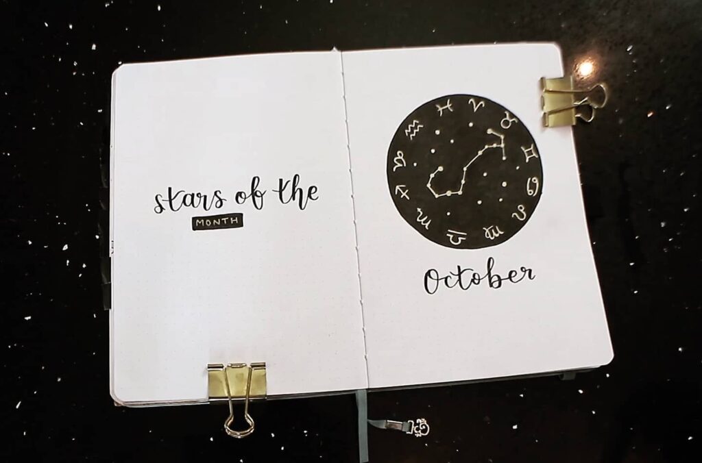 October journal spread with zodiac signs and Stars of the Month theme on a black starry background.