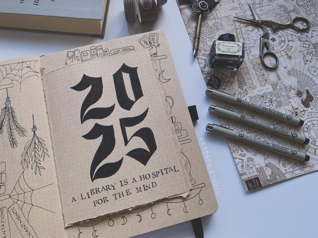 Handwritten 2025 in a notebook with art supplies and decorative paper. Text: A library is a hospital for the mind.