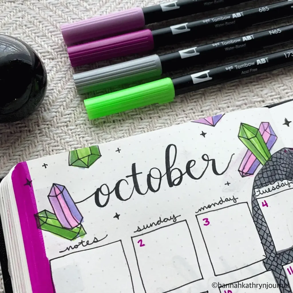 October bullet journal page with colorful pens and crystal designs.