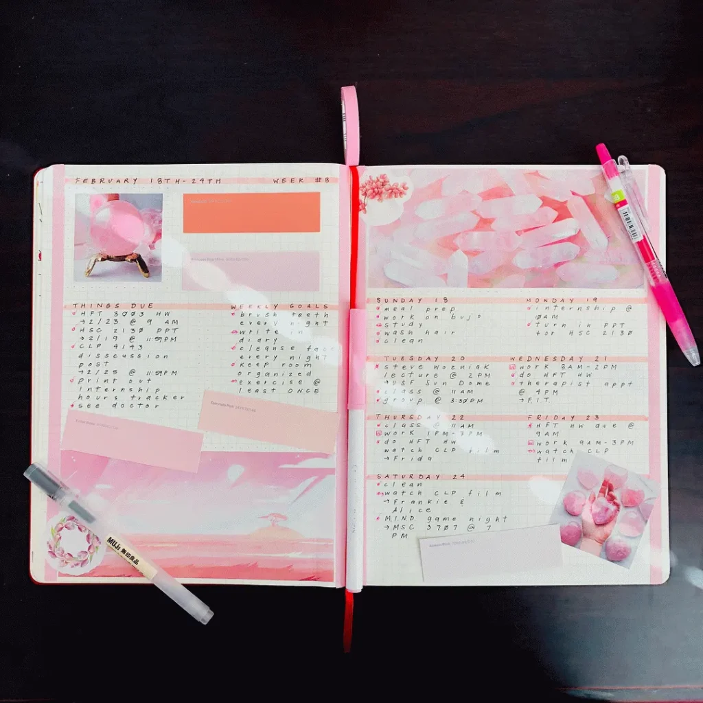 Open planner with a weekly layout, pink accents, and pens on a dark table, ideal for organization and planning.
