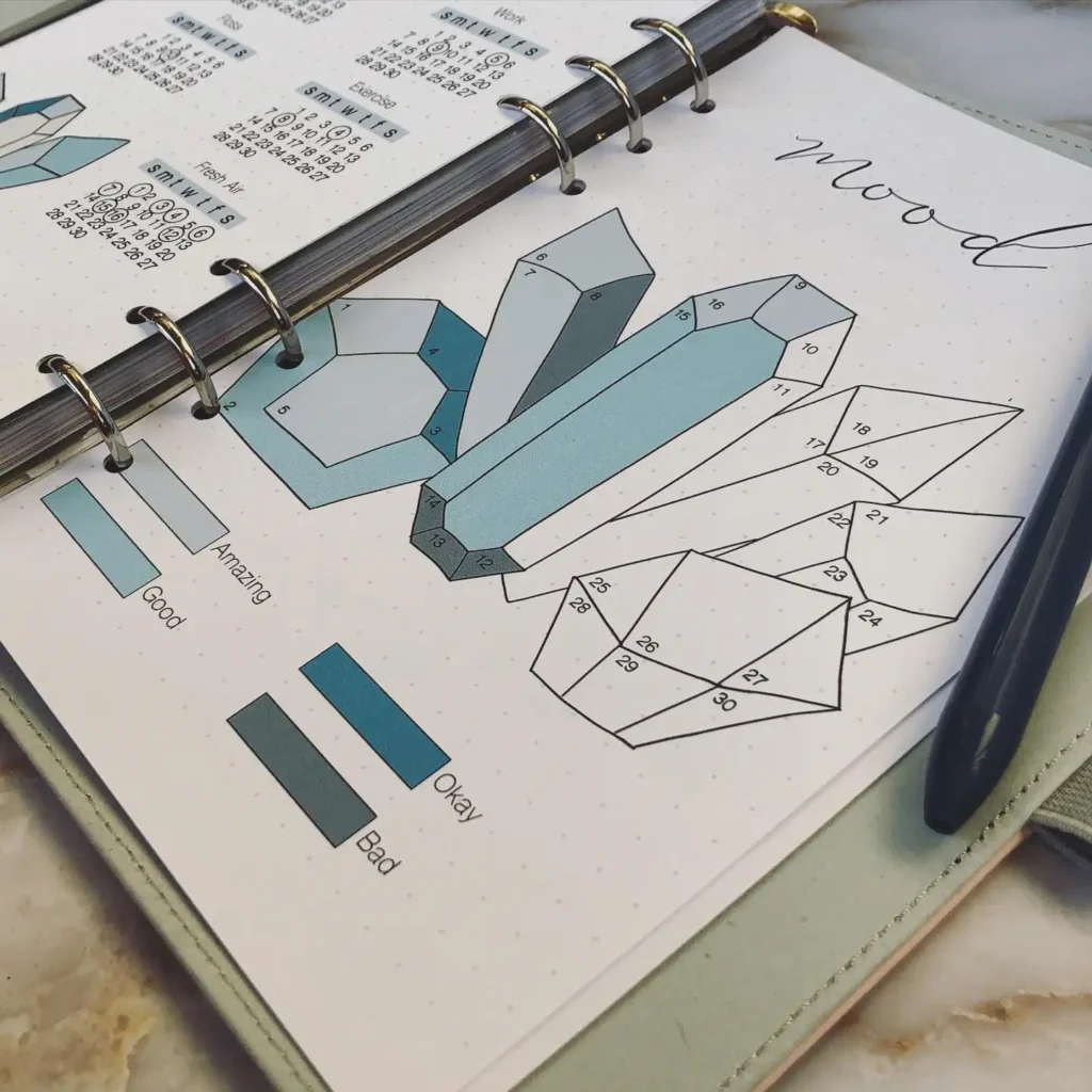 Mood tracker in a journal with colorful geometric shapes and a pen.